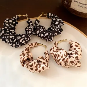 Close-up of retro leopard print fabric wrapped hoop earrings on a ceramic plate