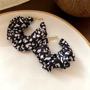 Close-up of vintage black and white leopard print fabric hoop earrings on a plate