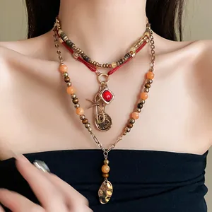 Detail view of multi-layered bohemian beaded necklace with vintage charms and leaf pendant