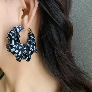 Close-up detail of a stylish leopard print fabric hoop earring worn by an Asian model