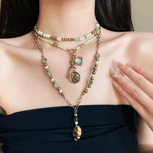 Close-up of a layered ethnic beaded necklace with bow and coin pendants worn on model