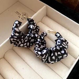 Detail close-up of black and white leopard print fabric hoop earrings in jewelry box