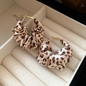 Detailed close-up view of vintage leopard print fabric hoop earrings inside a jewelry box