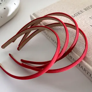 Close-up of three red minimalist fabric-covered headbands placed on a textured book