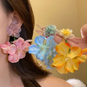 Dettaglio di orecchini a fiore in chiffon colorato con ago d'argento su modella