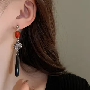 Dettaglio di orecchino stile cinese moderno con perla rossa e motivo a nodo Ruyi