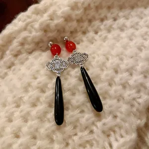 Dettaglio di orecchini cinesi vintage con perline rosse e pendenti a goccia neri eleganti