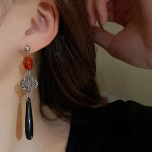 Dettaglio ravvicinato di orecchini vintage in stile cinese con goccia e perle rosse