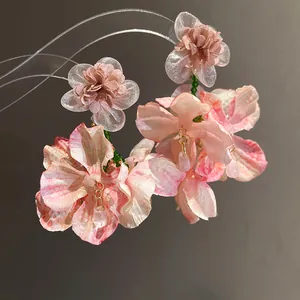 Dettaglio ravvicinato di eleganti orecchini a fiore in chiffon rosa con petali in tessuto