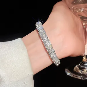 Close-up detail of a luxurious sparkling rhinestone pavé open bangle bracelet worn on a wrist