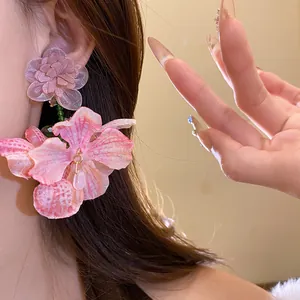 Dettaglio ravvicinato di eleganti orecchini a fiore in tessuto chiffon rosa con perno.