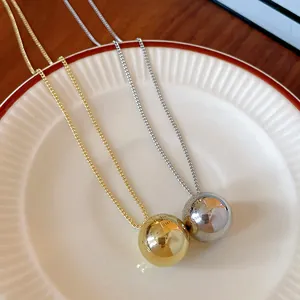 Close-up of gold and silver spherical pendants with delicate letter engraving on a plate