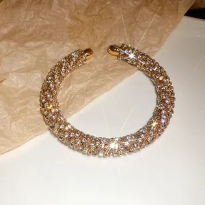 Close-up of luxury gold-toned open bangle fully encrusted with sparkling rhinestones