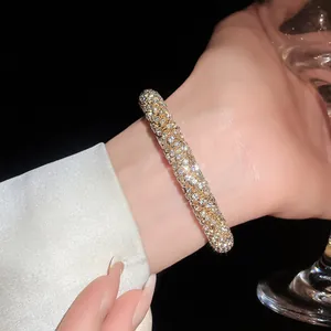 Detailed close-up of a luxurious sparkling rhinestone encrusted open bangle on a wrist.