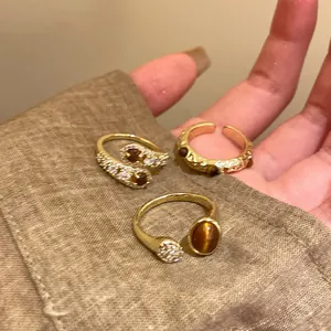 Primo piano di tre anelli aperti placcati in oro con pietre ambrate sulla manica.