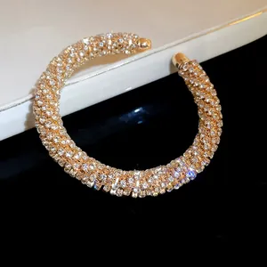 Detailed macro view of a luxury gold-tone open cuff bracelet encrusted with sparkling rhinestones