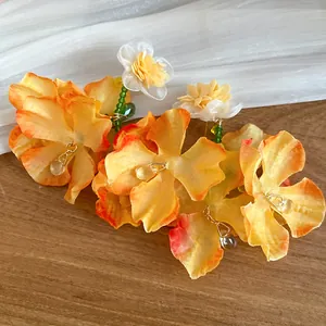 Primo piano di eleganti orecchini pendenti a fiore in chiffon arancione e gocce.