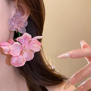 Dettaglio macro di eleganti orecchini a orchidea in chiffon rosa e fiore in tessuto viola