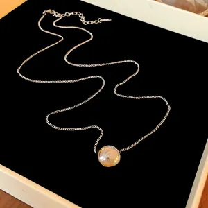 Close-up detail of a polished silver spherical pendant on a delicate link chain.