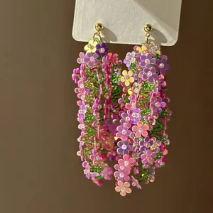 Colorful floral tassel earrings with sequin flowers and green beads on white card.
