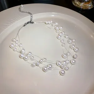 Detail view of multi-layered pearl necklace with transparent thread on white plate.