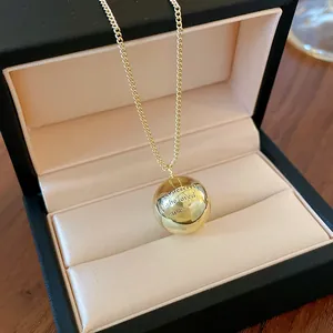 Close-up of gold ball pendant with 'you deserve to be loved' engraving in a black jewelry box