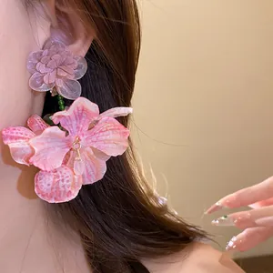 Primo piano di orecchini a fiore in chiffon rosa con petali di tessuto e perline.