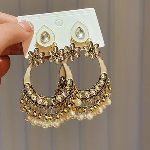 Close-up of ethnic style gold-toned hoop earrings with teardrop gems and pearls