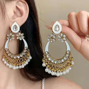 Close-up of teardrop floral pearl earrings with rhinestone detailing and steel needles.