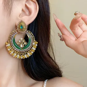 Close-up view of ornate ethnic-style jhumka earrings with green enamel and white pearls
