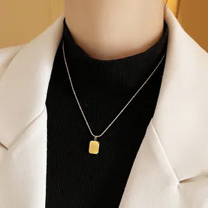 Elegant gold stainless steel necklace featuring a small rectangular tag pendant on a model.