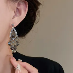 Close-up of elegant silver needle zircon tassel earrings with gray teardrop beads
