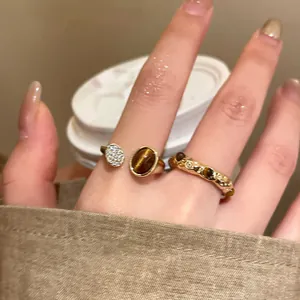 Primo piano di anello aperto placcato oro con pietra occhio di tigre e pavé di lusso