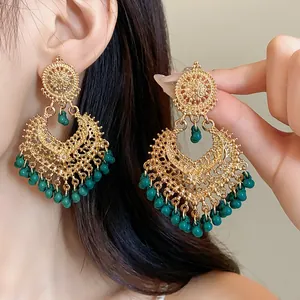 Close-up detail of vintage bohemian chandelier earrings with gold filigree and teal beads.