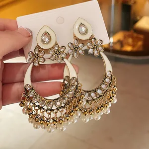 Close-up of ethnic style flower earrings with white enamel and pearl tassels