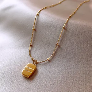 Detailed macro shot of gold stainless steel necklace with engraved CHARM pendant