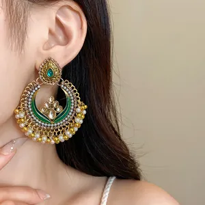 Macro view of ethnic vintage gold-tone earrings with green stones and pearl fringe