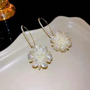 Elegant gold-tone earrings with layered white flower petals and sparkling rhinestone hooks.