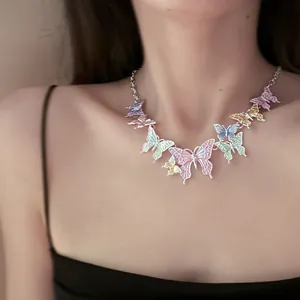 Close-up of a colorful spray-painted butterfly necklace worn by a female model in soft light