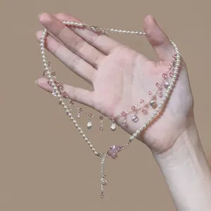 Close-up detail of a layered necklace featuring pearls and pink zirconia crystals