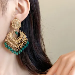Detailed view of vintage ethnic gold filigree earrings with elegant dark green beads.