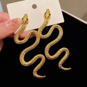 Boucles d'oreilles serpent dorées surdimensionnées avec des yeux étincelants en strass verts