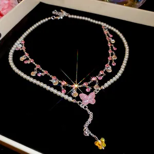 Close-up of elegant pearl necklace with pink zircon butterfly and shell pendants for women