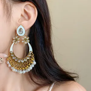 Close-up detail of ethnic style earrings with pearl dangles and floral rhinestone accents