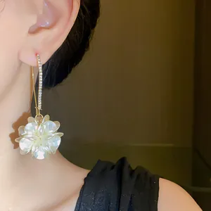 Close-up of elegant rhinestone white pearlescent flower ear hook earrings on model