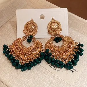 Detailed macro view of ethnic style gold chandelier earrings decorated with dark green beads