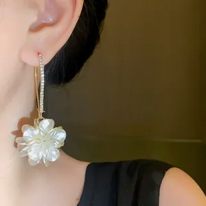 Close-up detail of elegant white flower dangle earrings with pave crystal setting