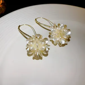 Detailed close-up of elegant white flower earrings with sparkling gold-toned rhinestone hooks