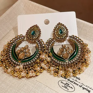 Close-up detail of ethnic vintage drop earrings featuring pearls and emerald green stones