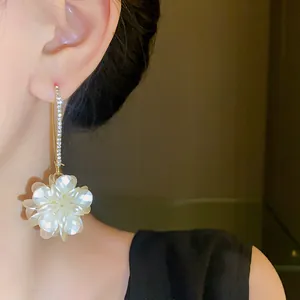 Close-up of elegant rhinestone ear hook featuring a white pearlescent flower drop detail